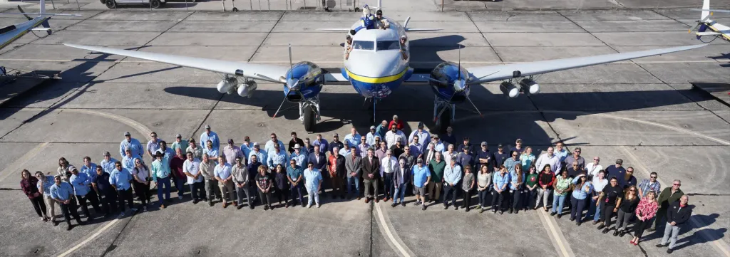 picture of LCMCD staff posing in front of a plane on the runway